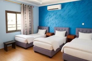 亚喀巴CozyQ Apt的一间设有三张床和蓝色墙壁的房间