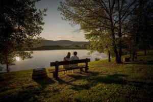 a couple sitting on a bench next to a lake at Tipico casolare toscano Tenuta della Selva in Murlo