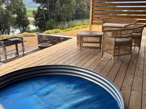einen Pool auf einer Terrasse mit einem Tisch und Stühlen in der Unterkunft Arendsig Wine Estate and River Eco Cabin in Bonnievale