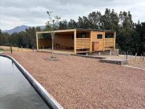 ein kleines Holzhaus neben einem Wasserkörper in der Unterkunft Arendsig Wine Estate and River Eco Cabin in Bonnievale