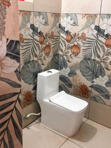 a white toilet in a bathroom with floral wallpaper at Prasadam Inn Varkala in Varkala