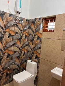 a bathroom with a toilet and a tropical wallpaper at Prasadam Inn Varkala in Varkala +26 photos