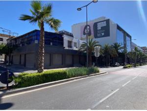 an empty street in front of a building with palm trees at Hotel Merry in Agadir