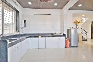 eine Küche mit weißen Schränken und einem Edelstahlkühlschrank in der Unterkunft EMPYREAN STAY ll MYSTICAL VILLA ll 4BHK ll AC ll PRIVATE POOL ll in Lonavla