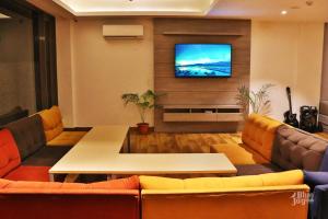 a living room with couches and a tv on a wall at The Blue Jay Hostel - Dorms & Rooms in Rishīkesh