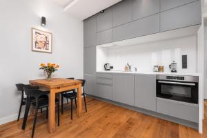 a kitchen with white cabinets and a wooden table at Palm Aparts Warsaw in Warsaw