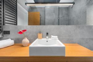 ein Badezimmer mit einem weißen Waschbecken und einer Vase mit einer Blume in der Unterkunft Palm Aparts Warsaw in Warschau + 75 Fotos