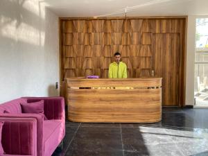 un hombre parado detrás de un mostrador de madera en una habitación en Xenious Opulent Hamirpur, en Hamīrpur