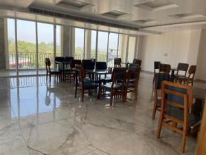 a dining room with a table and chairs and windows at Xenious Opulent Hamirpur in Hamīrpur