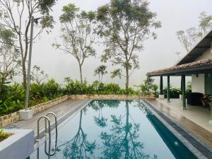 a swimming pool in front of a house with trees at Rain Drops Wellness Villa Deniyaya, Sinharaja in Deniyaya