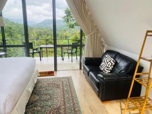 ein Wohnzimmer mit einem schwarzen Ledersofa und einem Balkon in der Unterkunft Rain Drops Wellness Villa in Mederipitiya