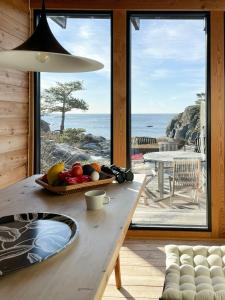 a table with a bowl of fruit on it with a view of the ocean at Original Architecture In Southern Norway in Søndeled