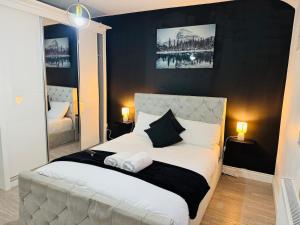 a bedroom with a white bed with a black wall at 4-BR House Near-Harry Potter-SkyStudios1-Family & Work Stays in Borehamwood