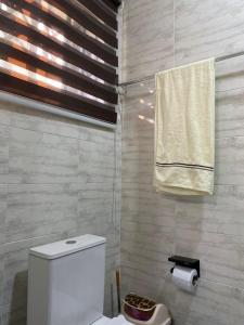 a bathroom with a white toilet and a towel at Nick Jaaks Courtyard-Single Room in Accra