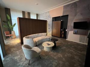 a living room with a couch and a chair at Fletcher Hotel Paleis Stadhouderlijk Hof in Leeuwarden