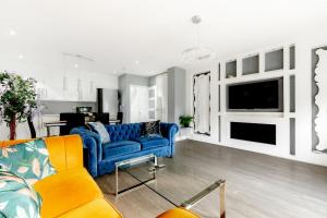 a living room with a blue couch and a tv at 4-BR House Near-Harry Potter-SkyStudios1-Family & Work Stays in Borehamwood