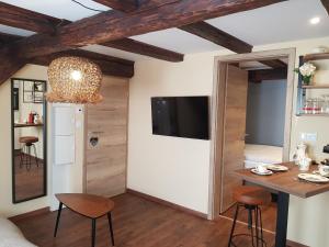 a living room with a table and a tv on a wall at L'ESCALE d'ALSACE in Lièpvre +12 photos