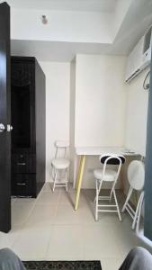 a kitchen with white chairs and a table in a room at City View with Balcony at Kasara Residences C5 Pasig in Manila