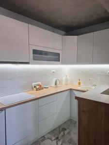 a kitchen with white cabinets and a microwave at Apartman JakšićS&M in Šid +14 photos
