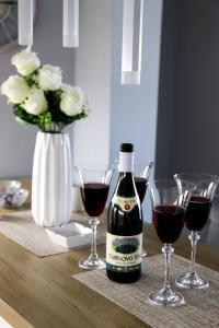 a bottle of wine sitting on a table with wine glasses at Apartman JakšićS&M in Šid