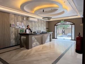 Ein Mann, der an einem Tresen in der Lobby sitzt. in der Unterkunft ركن صحاري للشقق المخدومة 6 جدة Rukn Sahari For Served Apartments in Quai