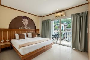 une chambre avec un grand lit et une grande fenêtre dans l'établissement The Eden Park, à Patong Beach