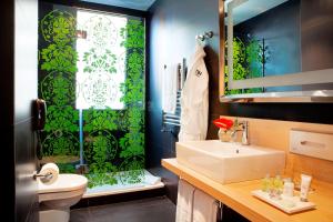 La salle de bains est pourvue d'un lavabo et d'un rideau de douche vert. dans l'établissement NH Madrid Principe de Vergara, à Madrid