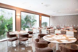 un restaurant avec des tables et des chaises et de grandes fenêtres dans l'établissement NH Madrid Principe de Vergara, à Madrid