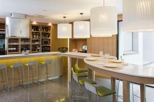 une cuisine avec un bar avec des tabourets verts dans l'établissement NH Madrid Principe de Vergara, à Madrid