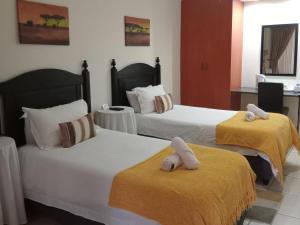a hotel room with two beds with towels on them at Swasti Guesthouse in Boksburg +28 photos