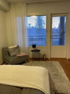 une chambre avec un lit, une chaise et des fenêtres dans l'établissement Cozy apartment with sauna, à Rovaniemi