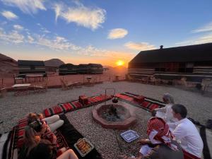 a group of people sitting around a fire pit in the desert at Wadi Rum Trip in Wadi Rum