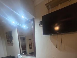 a bathroom with a tv and a mirror with lights at Swasti Guesthouse in Boksburg