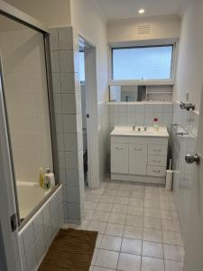 a bathroom with a tub and a sink and a mirror at Private Cozy Room in a Spacious Flat in Carnegie in Carnegie