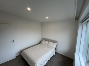 a small white room with a bed in it at Private Cozy Room in a Spacious Flat in Carnegie in Carnegie