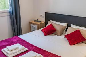 Apartamento Cabrera by Mallorca Infinity في باغيرا: غرفة نوم بها سرير مع وسائد حمراء وبيضاء