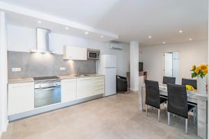 Apartamento Cabrera by Mallorca Infinity في باغيرا: مطبخ مع خزائن بيضاء وطاولة وكراسي