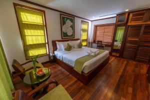 une chambre avec un lit et une table et quelques fenêtres dans l'établissement Maison Saiko Angkor Boutique, à Siem Reap