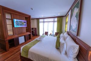 une chambre avec un grand lit avec une télévision au mur dans l'établissement Maison Saiko Angkor Boutique, à Siem Reap