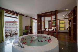 une salle de bain avec une grande baignoire avec des fleurs rouges dedans dans l'établissement Maison Saiko Angkor Boutique, à Siem Reap