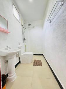 Un baño blanco con lavabo e inodoro. en Panda Guest House, en Corón