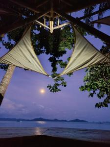 a view of the moon over the ocean from a beach at Kamp Tapik - Sibaltan in El Nido