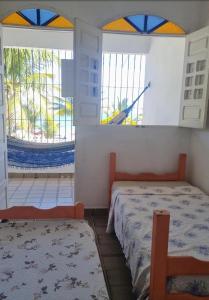 een slaapkamer met een bed en twee ramen bij Casabeiramaritamaracá in Itamaracá +5 foto's