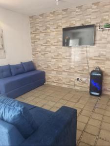 een woonkamer met een blauwe bank en een flatscreen-tv bij Casabeiramaritamaracá in Itamaracá