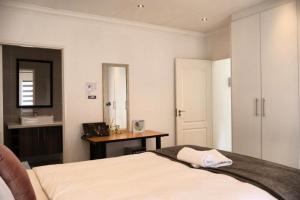 a bedroom with a bed and a desk and a mirror at The Condor Nest! in Sandton +26 photos