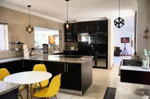 a kitchen with a white table and yellow chairs at The Condor Nest! in Sandton