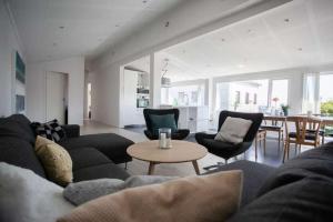 ein Wohnzimmer mit Sofa, Stühlen und einem Tisch in der Unterkunft 3BR Modern Penthouse Apartment in the Heart of Torshavn in Tórshavn