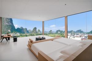 ein Schlafzimmer mit einem großen weißen Bett und großen Fenstern in der Unterkunft Shuitiao Boli Hotel (Yangshuo Shili Gallery Yulonghe Branch) in Gaotian