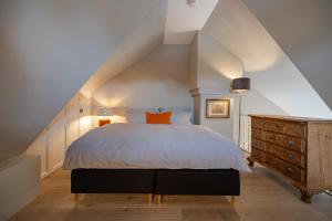 a attic bedroom with a bed and a wooden dresser at Leo in Keitum