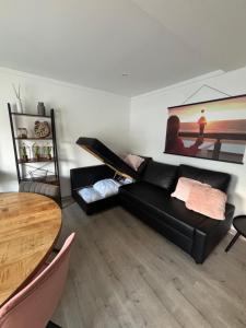 a living room with a black couch and a table at ChezPetitOscar in Middelkerke